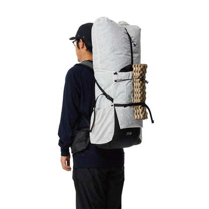 White PPU Tibet 55 backpack worn from the side with a sleeping pad attached